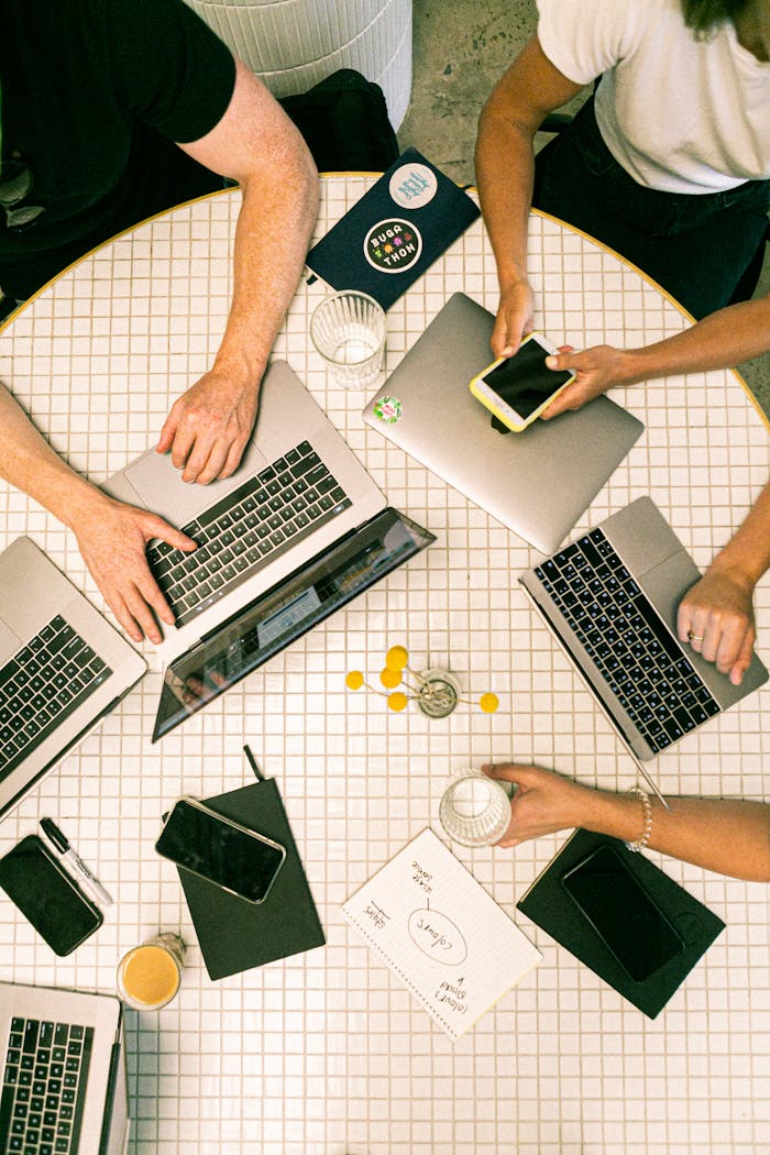 creative-01 Top view of a team collaborating with laptops, phones, and notes in a modern office.